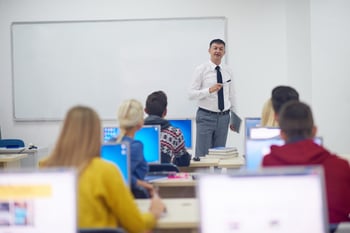 group of students with teacher in computer lab classrom learrning lessons, get help and support